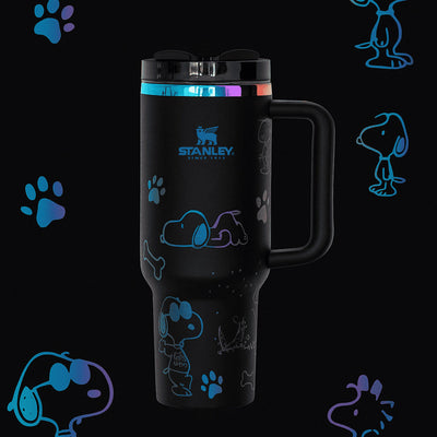 Black Stanley mug with Snoopy designs on a black background with Snoopy illustrations.