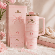 Pink Stanley mug and packaging with flowers and books in the background