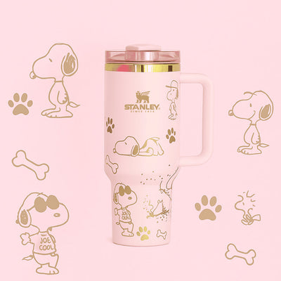 Pink Stanley tumbler with Snoopy illustrations on a pink background