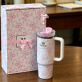 Pink and white Stanley tumbler with matching bow-themed packaging on a wooden surface.