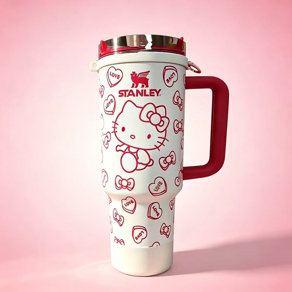 STANLEY Hello Kitty tumbler featuring red heart patterns, bow accents, insulated construction, large handle, and cute collectible drinkware design.