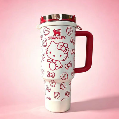 STANLEY Hello Kitty tumbler featuring red heart patterns, bow accents, insulated construction, large handle, and cute collectible drinkware design.