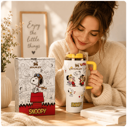 Woman holding a Snoopy-themed mug with a matching box on a table.