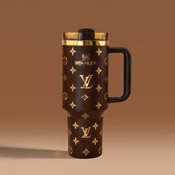 Stanley 40oz insulated tumbler featuring luxury-inspired brown monogram pattern, gold accents, black ergonomic handle, and premium insulated design
